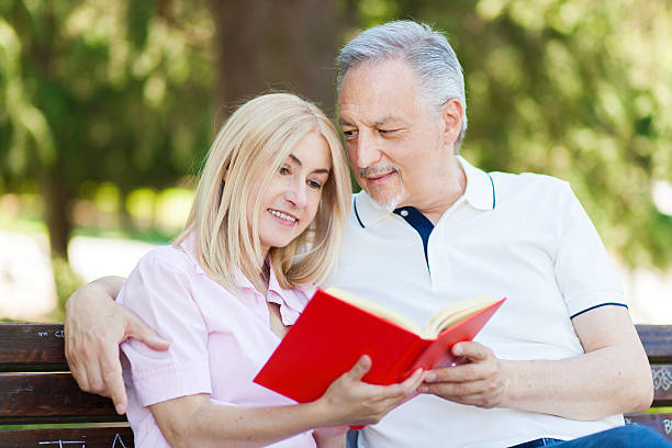istock senior couple reading a book at the park bench 481337668