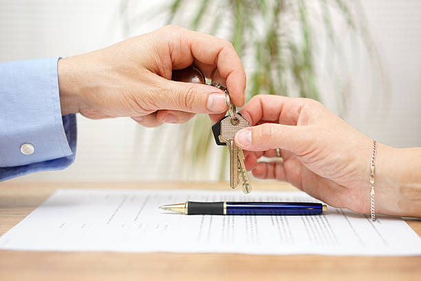 real estate agent bietet haus schlüssel zu seinem kunden - human hand key giving carrying stock-fotos und bilder