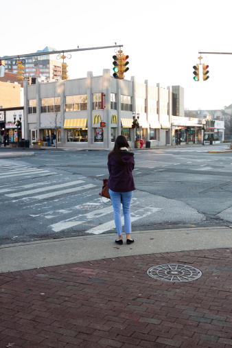 Stamford, CT, USA - December 14, 2012: A young woman is waiting to cross an intersection in the downtown business area of Stamford. Stamford was known as Rippowam by the Native Americans until July 1, 1640. Today the city is the fourth largest in the state and the eighth in New England.