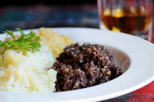 Haggis Scottish meal of Haggis, neeps and tatties - and of course a wee dram. Narrow depth of field on haggis. Traditional meal for Rabbie Burns night. haggis stock pictures, royalty-free photos & images