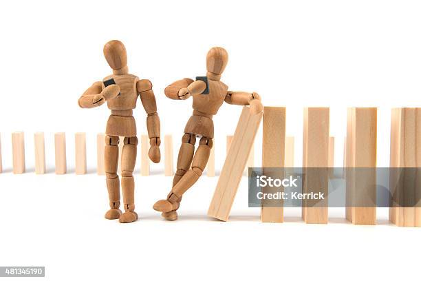 Wooden Mannequin Leans Careless On Domino Cascade With Smartphone Stock Photo - Download Image Now