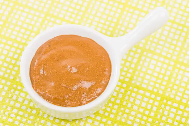 French Mustard - Bowl of french mustard on a green background.