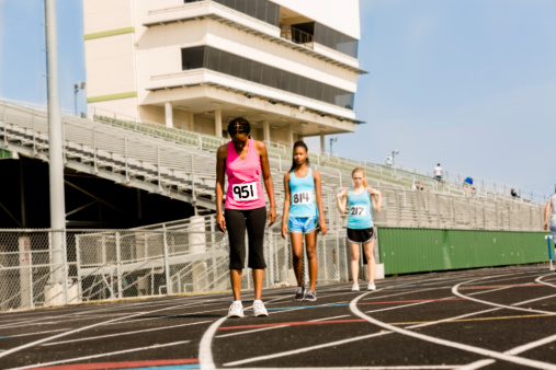 Three women prepare for a track race. Sports stadium.