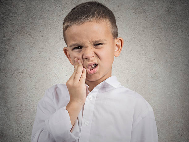 Child with toothache Child toothache. Closeup portrait boy with sensitive tooth ache crown problem touching outside mouth with hand isolated grey wall background. Negative human emotion, facial expression feeling reaction ugly people crying stock pictures, royalty-free photos & images