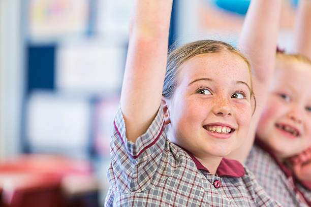 Hands Raised Smiling School Girls in the Classroom stock photo