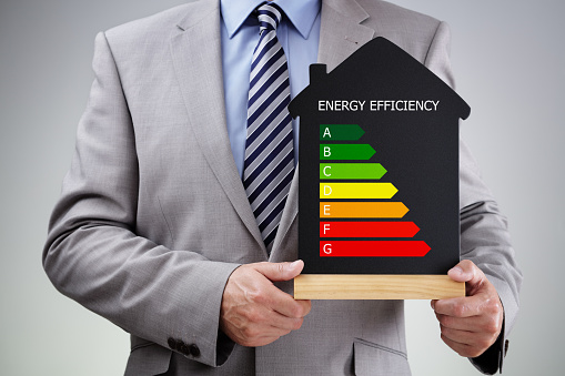Businessman holding house shape blackboard with chalk energy efficiency rating chart concept for performance, efficiency and environmental conservation