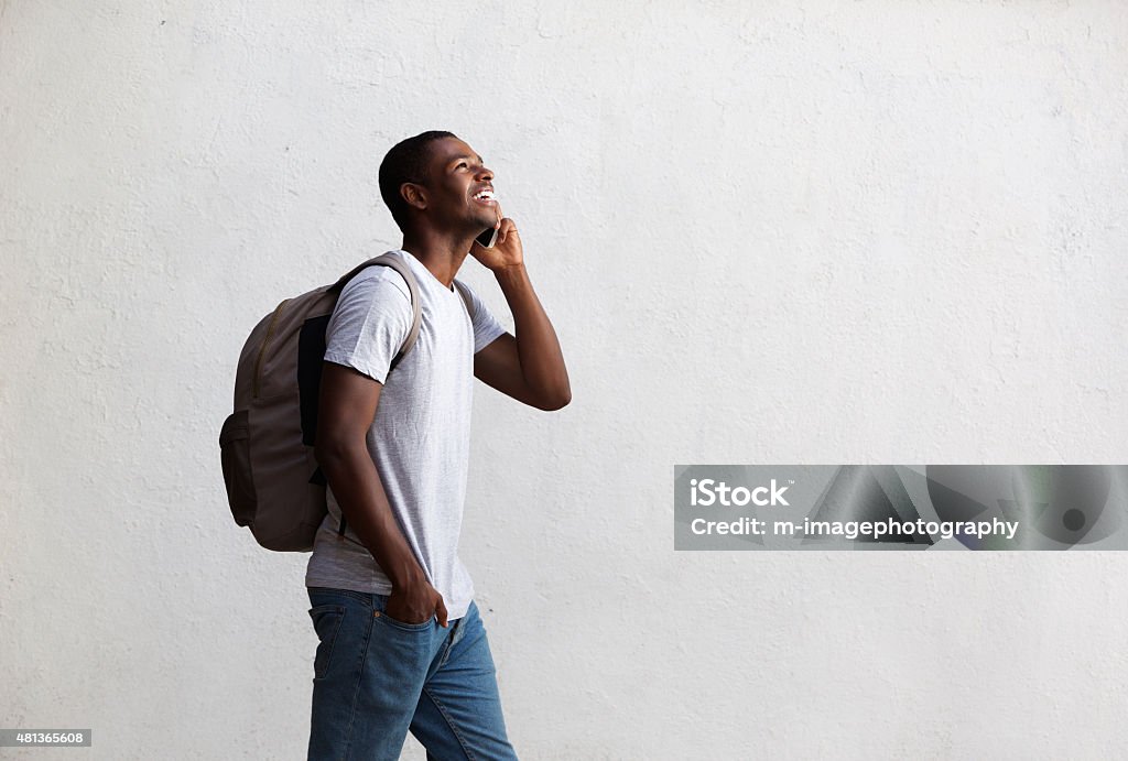 Happy student walking and talking on mobile phone Side portrait of a happy student walking and talking on mobile phone University Student Stock Photo