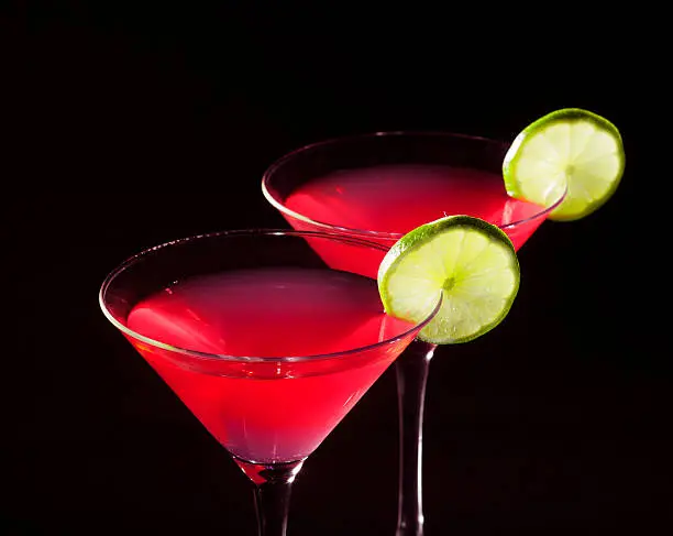 Two glasses of cosmopolitan coctail on a black background.