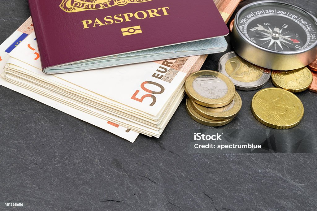 Euro Travel Money An arrangement of Euro notes, coins, passport and compass on slate. Passport Stock Photo