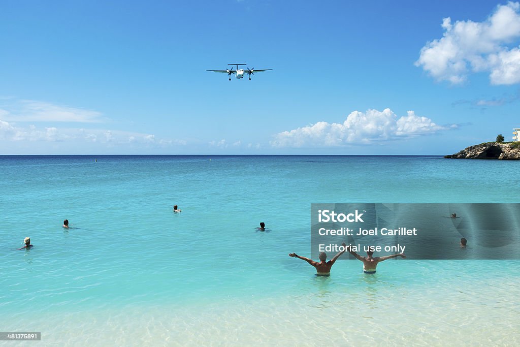 Greeting a plane on St. Maarten Maho Bay, St Maarten, Netherlands Antilles - November 15, 2013: Two men wave at an approaching plane about to land at Princess Juliana International Airport in St. Maarten. Sint Maarten Stock Photo