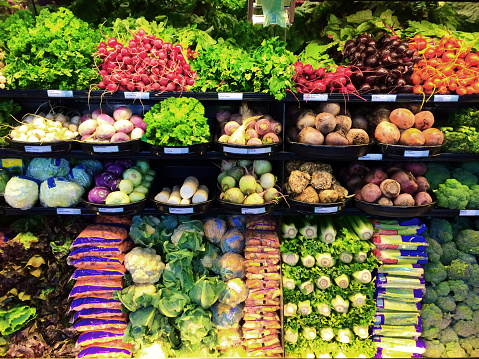 A display of fresh produce of vegetables and fruits in a grocery store supermarket refrigerator shelves case. A retail market environment. A large variety of food items are beautifully organize for the customer. Photographed on location in horizontal format.