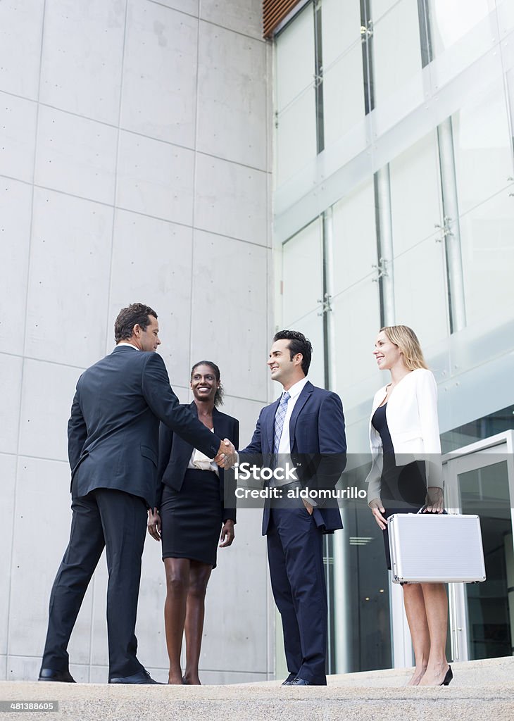 Deux hommes d'affaires se serrant la main à l'avant du bâtiment - Photo de Cadre d'entreprise libre de droits