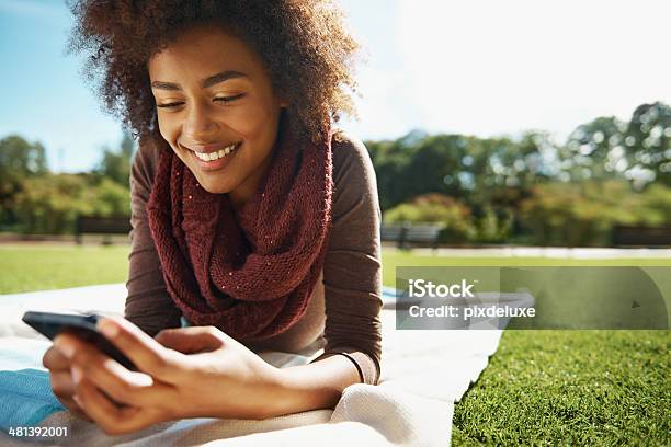 Reading Her Texts With Glee Stock Photo - Download Image Now - Lying Down, Grass, Women