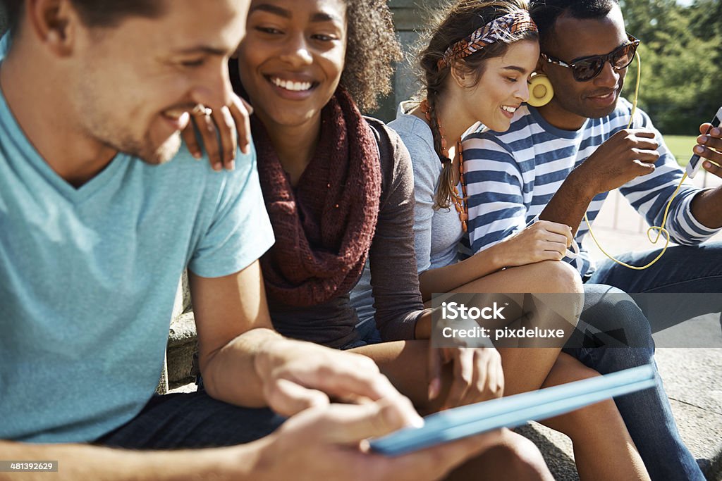 Un gruppo di quattro persone seduto e sorridente - Foto stock royalty-free di Adulto