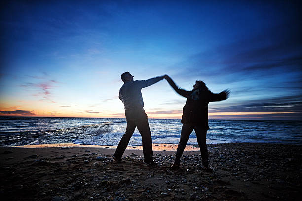 istock Senior couple dancing on seashore at sunset 481392848