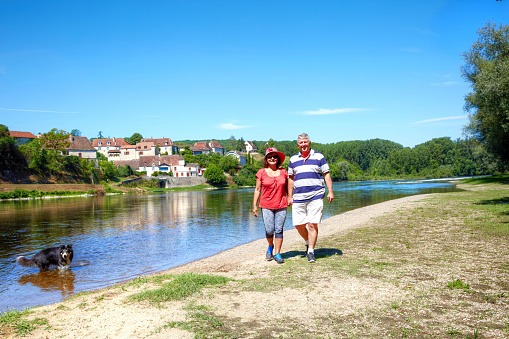 Mature couple walking dog alongside River Dordogne