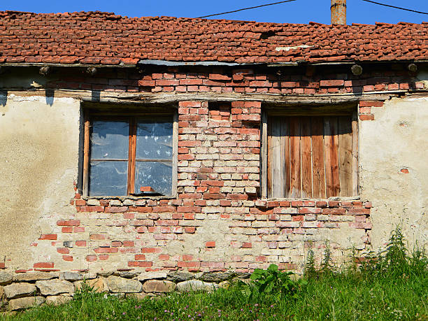 Two windows of a ruined rural house in sunny summer day with blue sky.