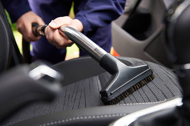 Man Hoovering Seat Of Car During Car Cleaning Man Hoovering Seat Of Car During Car Cleaning car interior stock pictures, royalty-free photos & images
