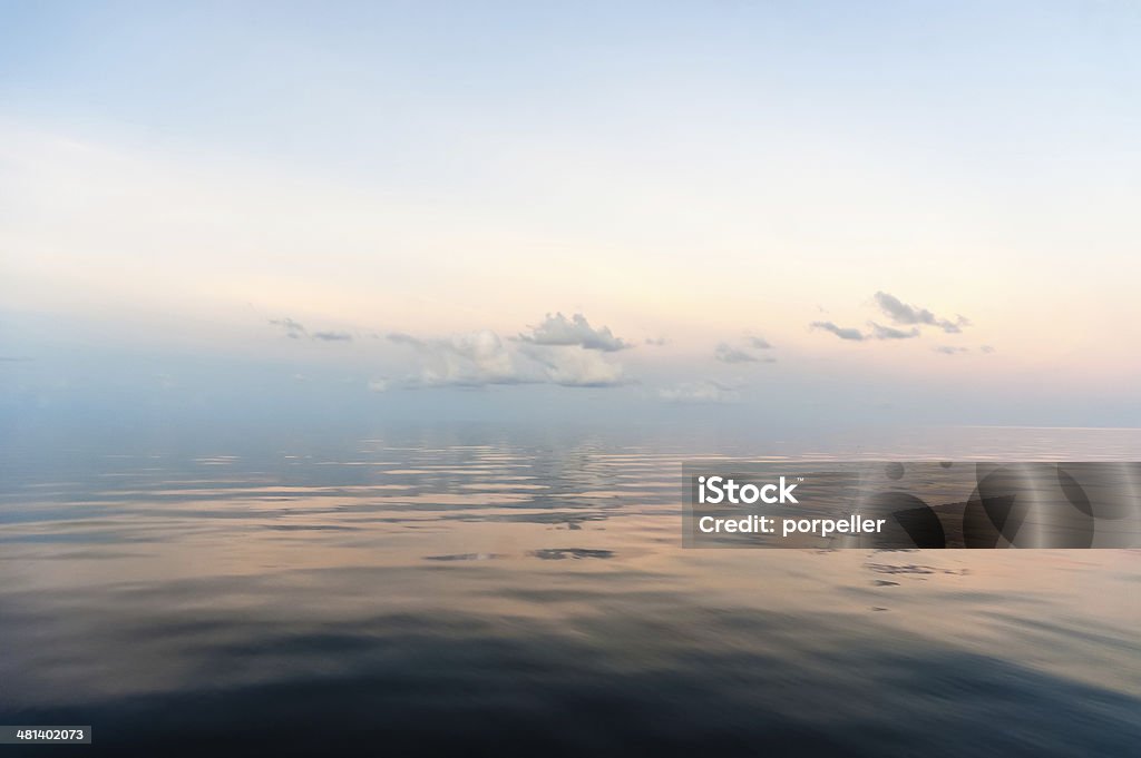 Zen Dawn a pastel coloured tropical dawn with some fluffy clouds making reflections in the calm waters Horizon Stock Photo