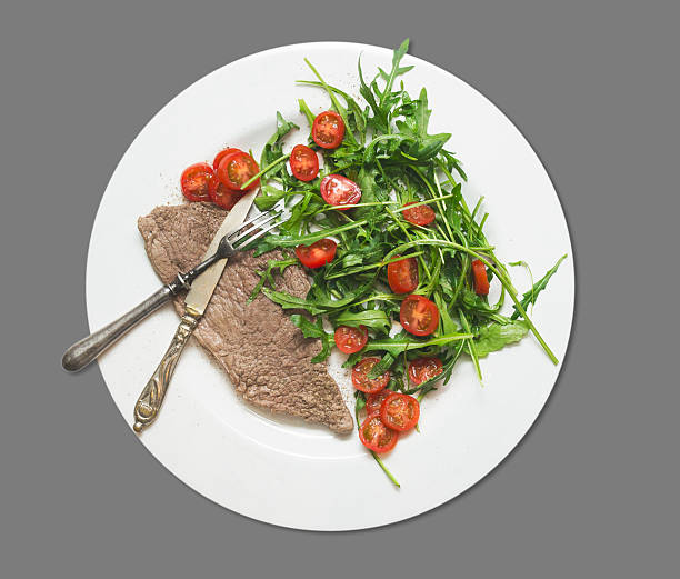 istock beef with rocket salad and tomatoes , isolated on gray 481408217