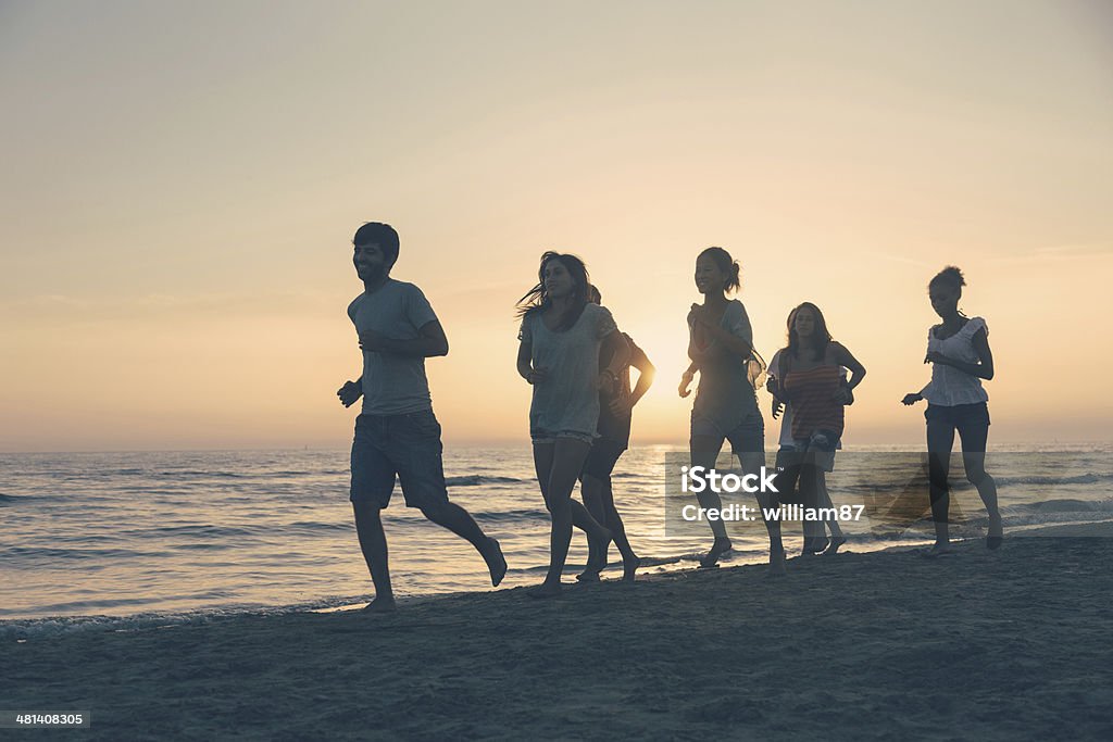 Group of People Running on the Beach at Sunset Adult Stock Photo