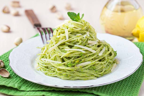 Italian pasta spaghetti with pesto green peas, mint, pistachios stock photo