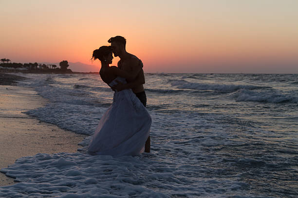 istock Just married young couple on a hazy beach at dusk 481423596