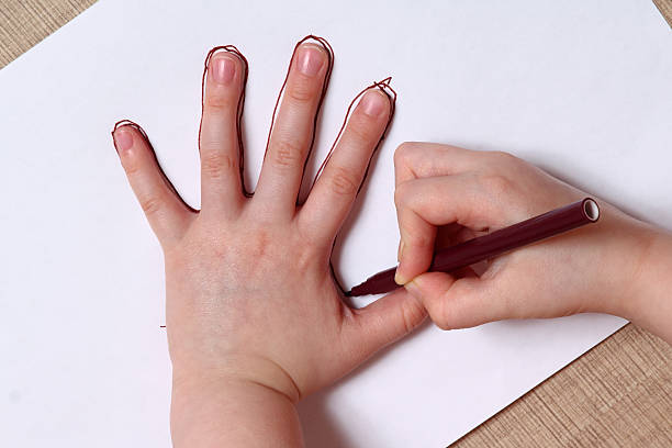 Little girl is drawing contour of the hand. stock photo
