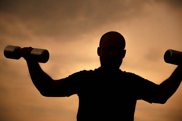 Silhouette weight lifting at sunrise
