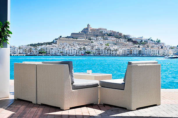 Sa Penya and Dalt Vila districts in Ibiza Town, Spain an empty couch at the Mediterranean Sea, with Sa Penya and Dalt Vila districts, the old town of Ibiza Town, in the background, in the Balearic Islands, Spain ibiza town stock pictures, royalty-free photos & images