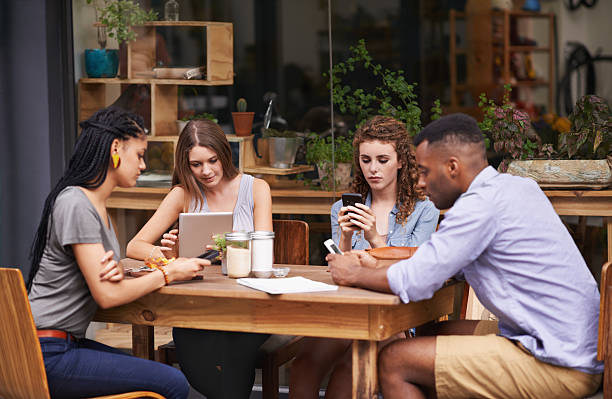 Relaxing with the best of friends A group of young friends sitting outside at a sidewalk cafe busy restaurant tables stock pictures, royalty-free photos & images