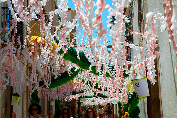 Tomar, Portugal - July 11, 2015: Paper flowers decorating a street in Tomar Portugal. Every four years the city is alive with festivities celebrating the Holy Spirit. The week-long event starts with a street decorating competition. In this image people are walking along one such street admiring the decorations.