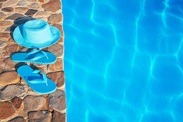 istock Blue  hat  and flip flop by a swimming pool 481437082