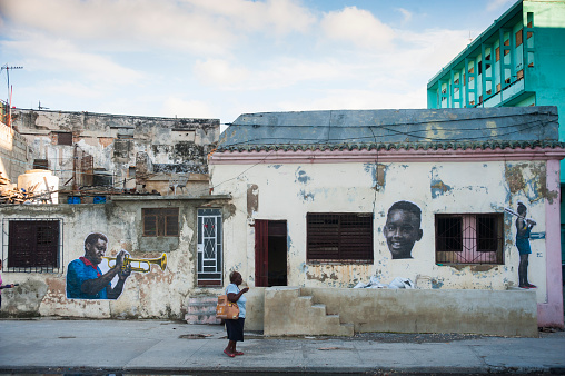 Havana, Cuba - May 5, 2015: A woman stroll past murals on a building in Havana, Cuba