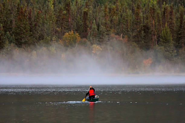 istock Man in canoe near morning mist on lake 481443435