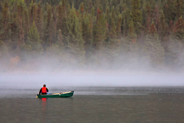 istock Man in canoe near morning mist on lake 481443449