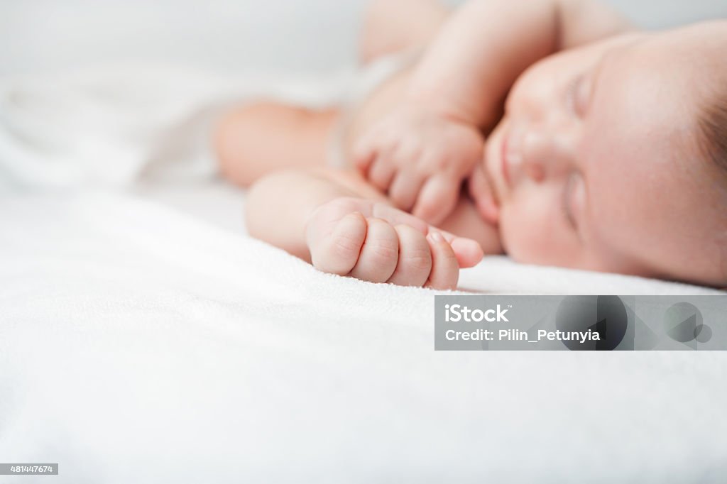 Newborn baby sweet sleeping on a white bed Newborn baby sweet sleeping on a white bed or background with large copy space for any text. Concept of baby care 2015 Stock Photo