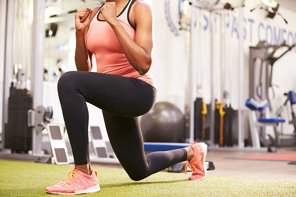 mujer haciendo lunges en un gimnasio, cultivo - lunge fotografías e imágenes de stock