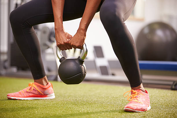 Woman exercising with a kettlebell weight, low-section crop