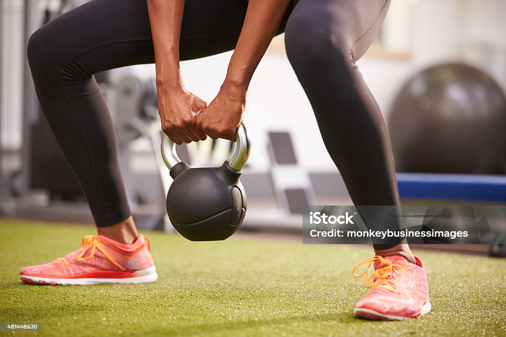 Kobieta wykonując z odważnikiem kettlebell wagi, nisko części roślin - Zbiór zdjęć royalty-free (Giria)