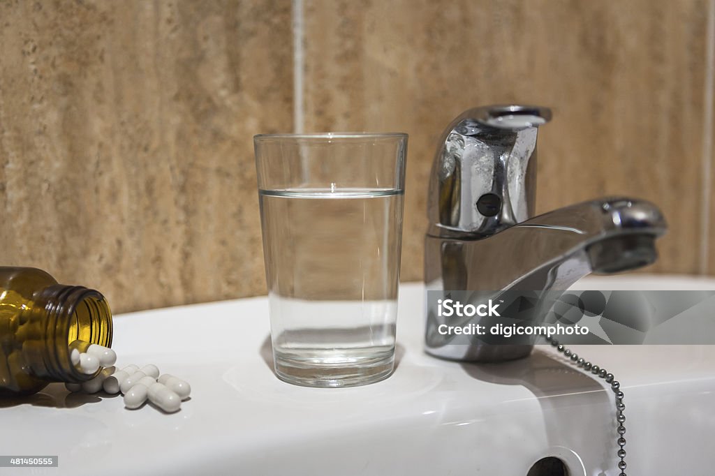 Glass of water and pile of blister packs in bathroom Glass of water and pile of blister packs in bathroom shelf Bathroom Stock Photo