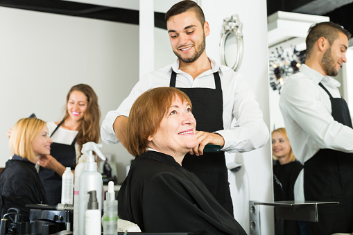 Mature woman cuts hair at the hair salon