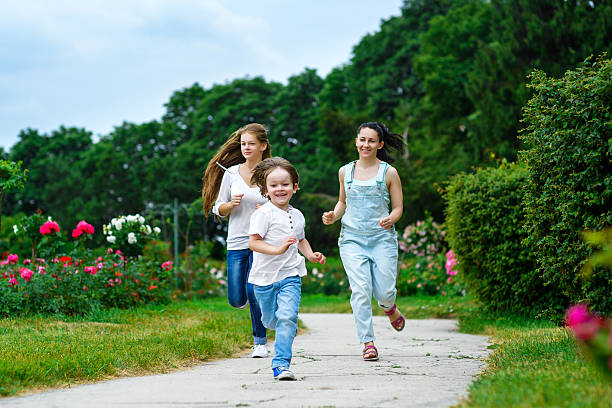 istock Happy Mother with daughter and son running on grass smiling 481457102