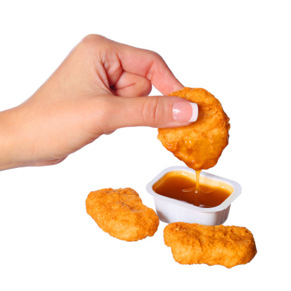 Chicken Nuggets in female hand and Sauce isolated on white