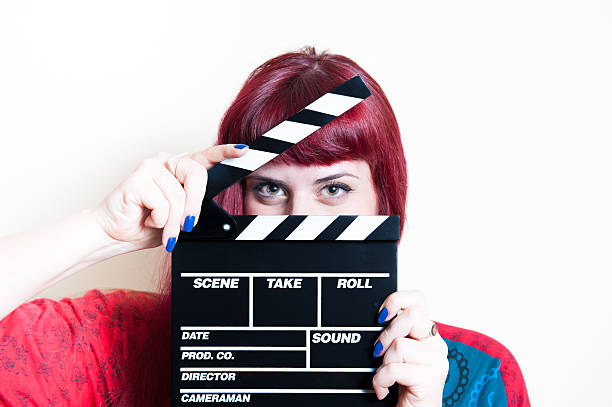 istock Young woman smiling showing movie clapper board 481460122