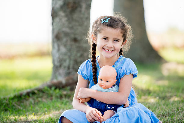маленькая девочка играет с куклы в парк - baby doll dress стоковые фото и изображения