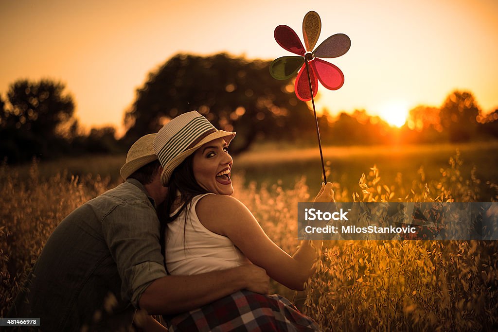 Loving couple in  field  at sunset loving couple enjoying each other's arms in a field at sunset with a whirligig wind 2015 Stock Photo