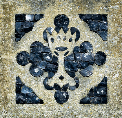Knapped flint decoration set into stone on a Suffolk (England) church. The device resembles a communion chalice.