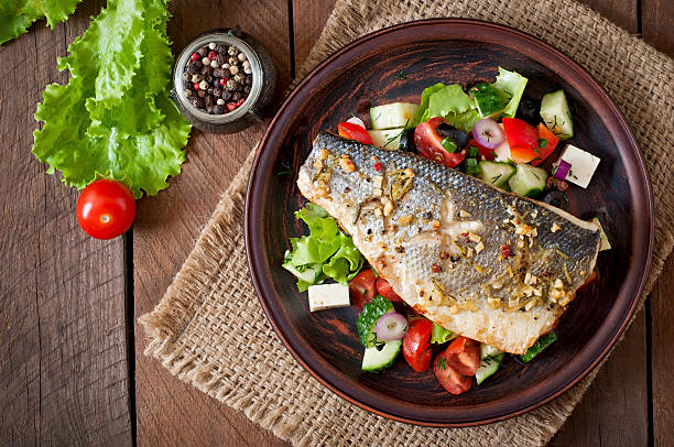 Baked seabass with Greek salad Baked seabass with Greek salad sea bass stock pictures, royalty-free photos & images
