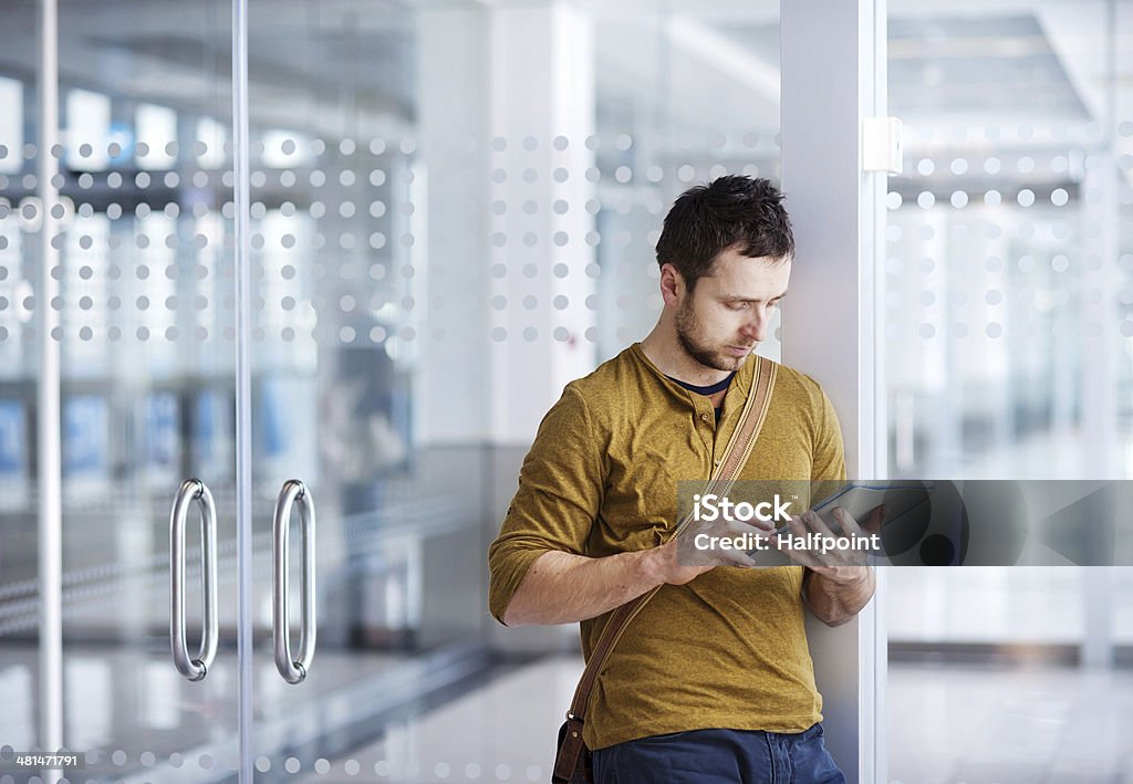 Giovane uomo utilizzando un tablet all'aeroporto - Foto stock royalty-free di Abbigliamento formale